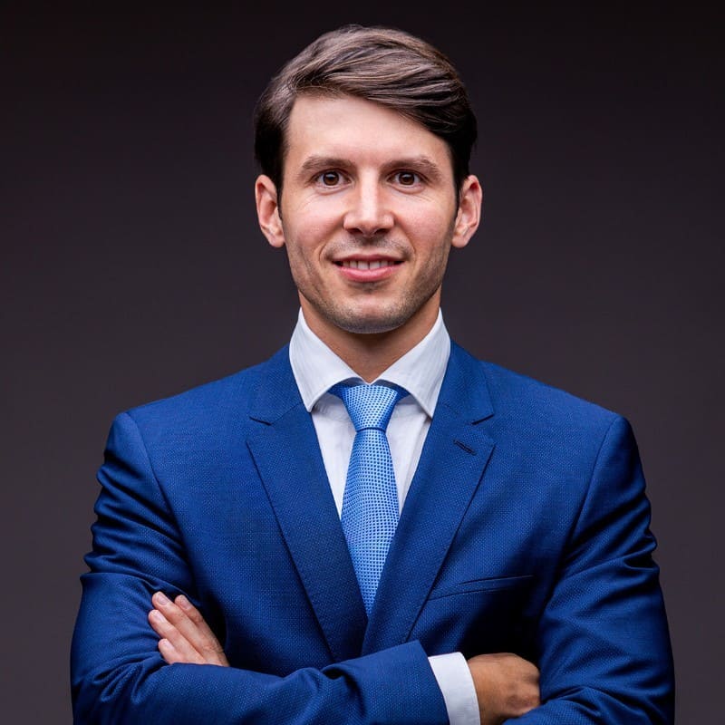 Julian Schweizer, Managing Partner der Swiss Online Publishing AG, in einem gutaussehenden blauen Sakko mit hellblauer Krawatte. Er sieht sauber frisiert aus und schaut direkt in die Kamera.